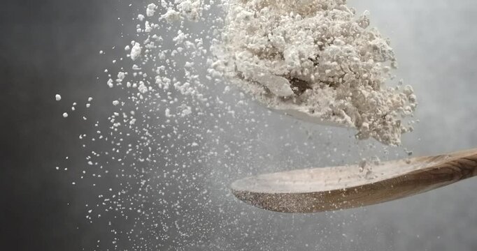 Flour falling from wooden spoon in super slow motion
