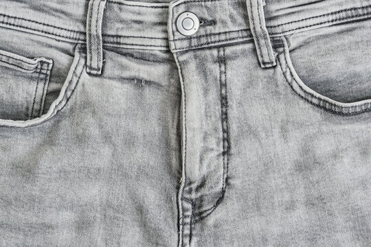 Front view close up grey washed jeans featuring zipper fly, button, and pockets.