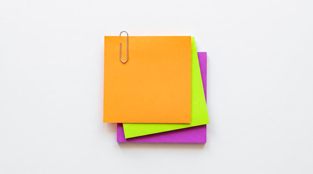 Colorful sticky notes clipped together with paperclip on white background