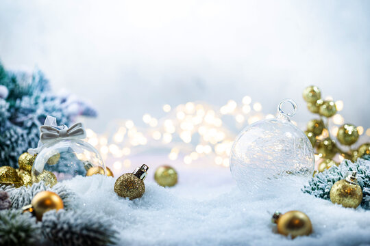 Christmas gold decorations on snow with fir tree branches and christmas lights. Winter Decoration Background