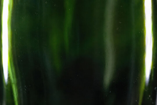 Emerald Glass Surface Abstract. A deep olive bottle texture with glowing highlights, evoking a sense of mystery and organic elegance.