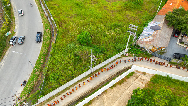 Aerial view of A procession of 150 Buddhist monks walks along a narrow mountain path toward the Big Buddha on Nak Kerd Hill in Phuket, where local residents gather to offer alms and make merit.