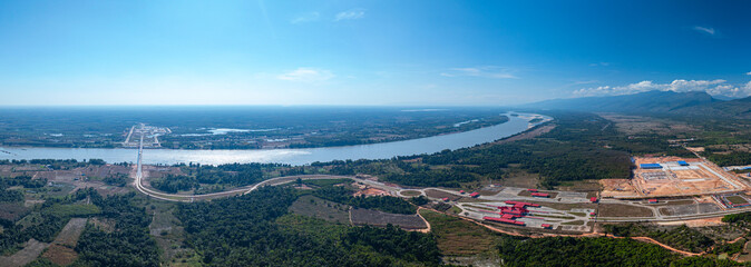 Fototapeta premium Drone perspective of the Fifth Thai Lao Friendship Bridge spanning tranquil river waters and rural landscapes, highlighting transportation infrastructure and regional development.