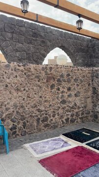 Prayer rugs laid by the historic stone walls of Masjid Bani Anif in Madinah.