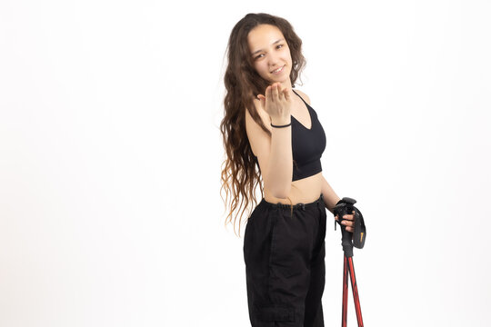 Active female holding trekking poles posing in studio setting