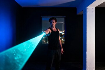Fototapeta premium Man in Dark Room Holding Blue Laser Beam
