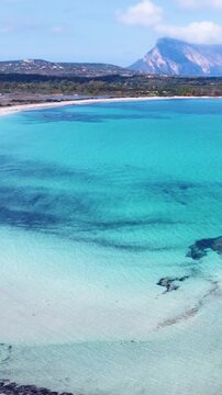 Vertical drone aerial view of crystal clear turquoise sea and white sand at Lu Impostu beach, San Teodoro, Sardinia, Italy. Scenic Mediterranean summer coastline.