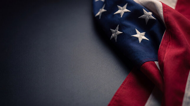 A high-quality close-up of a folded American flag on a dark background, providing ample space for text, ideal for patriotic themes and holidays.