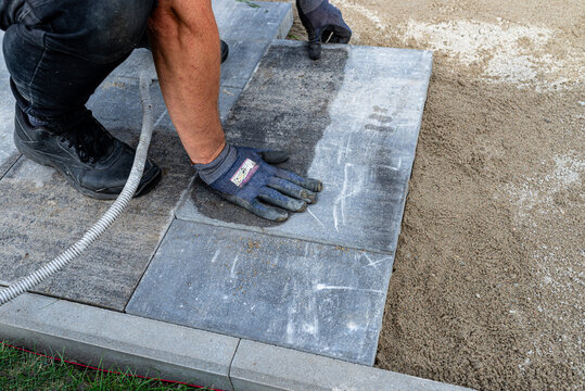 Worker laying paving slabs on a sand bed for a new patio