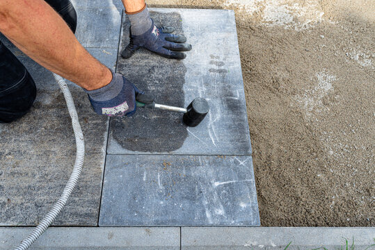 Worker installing paving slabs with a rubber hammer