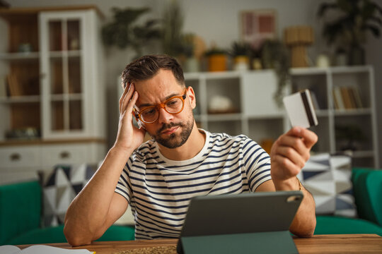 Stressed man experiencing financial problems with credit card and tablet
