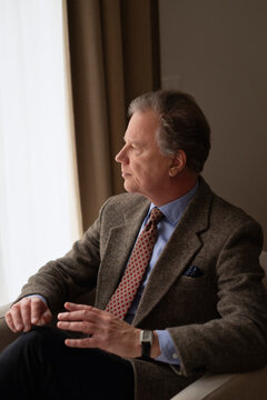 Thoughtful mature businessman sitting in armchair looking away