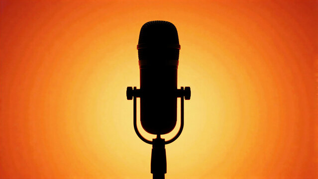 karaoke action silhouette of a professional studio microphone against orange light
