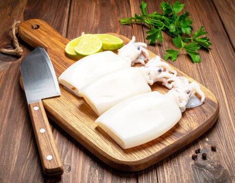 Fresh raw squid cleaned, wooden cutting board. AI