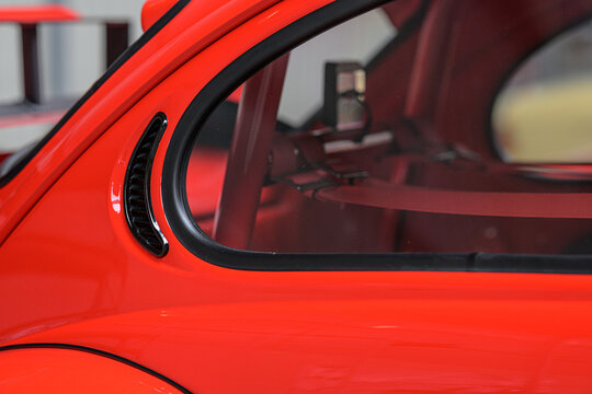Gothenburg, Sweden - May 30 2026: Side window vent detail on custom red Volkswagen Beetle body.