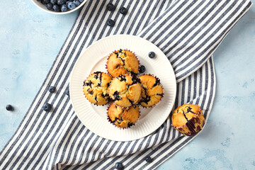 Naklejka na ściany i meble Top view of blueberry muffins on plate with striped towel