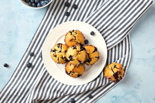 Top view of blueberry muffins on plate with striped towel