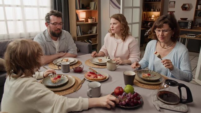 Caucasian multigenerational family eating breakfast and talking at dining table. Clip for promoting family values, healthy nutrition, or real estate marketing campaigns
