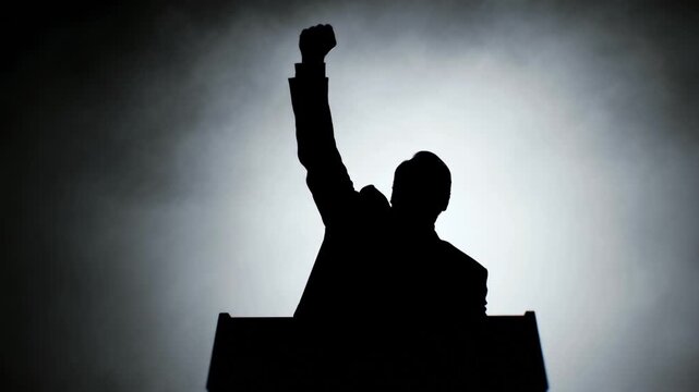 Silhouette of politician raising fist at podium during speech