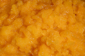 Obraz premium Bright orange mango puree texture closeup with glossy fruit surface