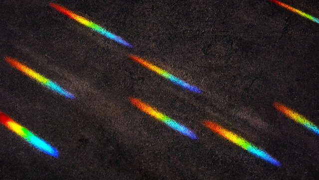Prismatic light leaks on dark background. Colorful rainbow flares for creative overlay design.