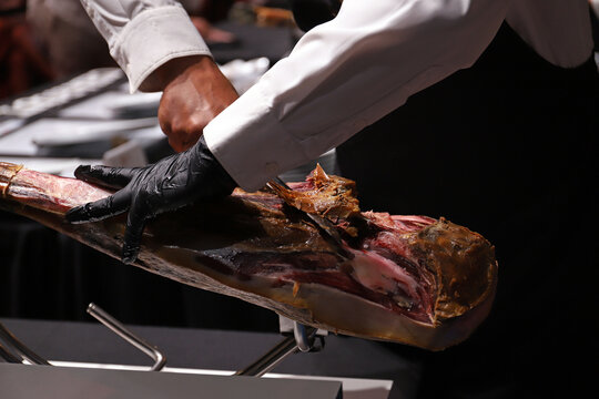 maestro jamonero manipulando un jam&oacute;n ib&eacute;rico para limpiarlo de su costra