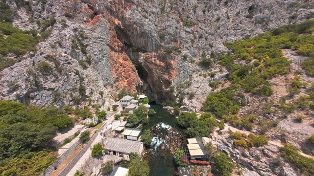 Aerial view of Blagaj Tekke dervish house and Buna river spring under steep rock cliff in Bosnia