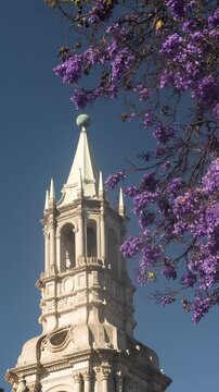 Ground level low-angle shot of a white sillar colonial church bell tower against a clear sky in Arequipa, Peru.