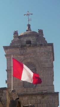 Detailed close-up in slow motion of the Peruvian flag fabric blowing in the wind against a historic Spanish colonial architecture background