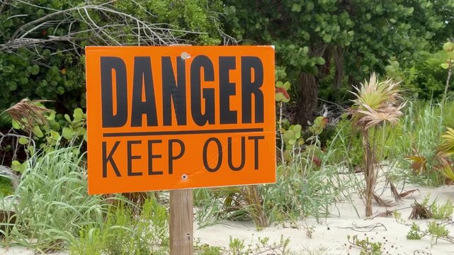 Orange "Danger Keep Out" warning sign at Sanibel Lighthouse Beach, Florida. The sign marks a restricted area near the shoreline, emphasizing public safety in a popular coastal destination.