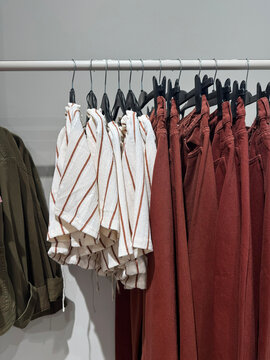 Neutral Linen Shorts And Brown Trousers Displayed On Boutique Clothing Rack