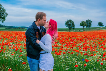 Romantic Young Couple Kissing in Red Poppy Field Under Blue Sky © Анастасия Константне