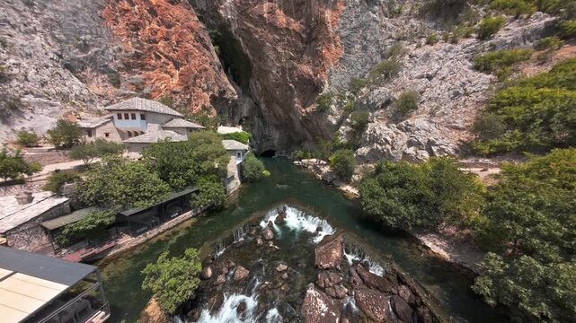 Aerial view of Blagaj Tekke dervish house and Buna river spring under steep rock cliff in Bosnia