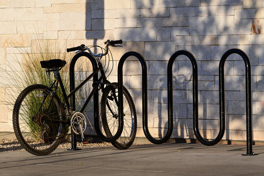 Bicycle secured to a public bike rack outside a commercial building, illustrating active transportation, cycling infrastructure, sustainable mobility, and urban planning