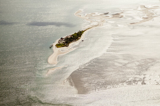 Vista a&eacute;rea da Coroa do Avi&atilde;o, banco de areia e ilha no litoral de Pernambuco, cercada por &aacute;guas rasas e mar&eacute;s, destacando a beleza natural do estu&aacute;rio e da costa nordestina.