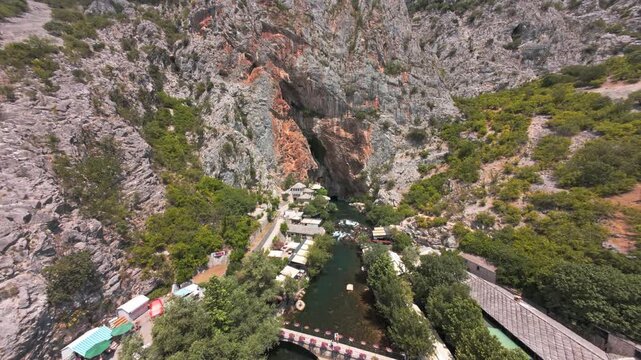 Aerial view of Blagaj Tekke dervish house and Buna river spring under steep rock cliff in Bosnia