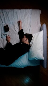 Priest resting in bed, wearing a cassock and holding a rosary and bible, symbolizing faith, devotion, and the spiritual life of a religious leader