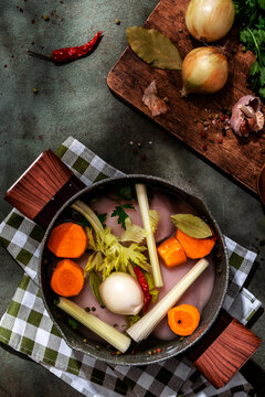 Preparing homemade chicken broth with fresh herbs, garlic, and onions