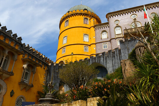 Magnificent close-up of the Pena Palace in Sintra, showcasing its iconic bold yellow cylindrical tower topped with a green dome.