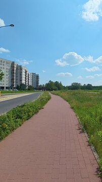 Bicycle path running past apartment blocks in suburban meadow