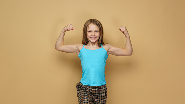  Adorable girl in blue shirt demonstrating biceps muscle