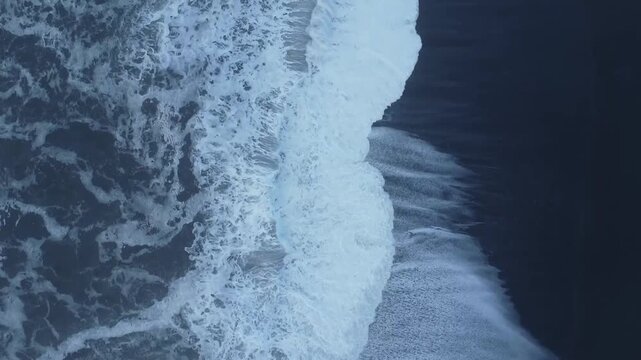 Top down drone view of waves crashing on Iceland black sand beach