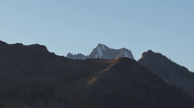 Aerial of jagged mountain range in Wenatchee National Forest Cle Elum Washington with heavily forested slopes and prominent rugged peaks under a clear sky at sunset