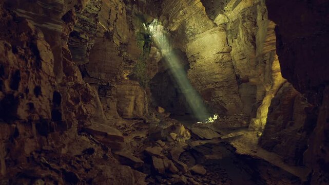 Collapsed chamber mammoth cave system exposing layered rock and loose debris, mottled walls and faint daylight shaft tracing erosion patterns and timeworn