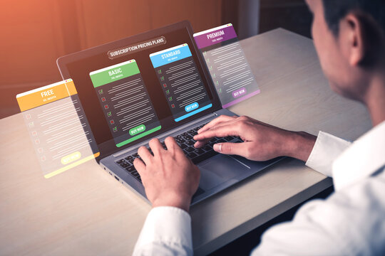Person using laptop to compare subscription plans with colorful options on the screen showcasing features and pricing in a modern workspace. Glyphic.