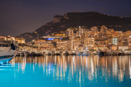 MONACO - JUNE 20, 2026: Night view of Port Hercule filled with luxury yachts and the illuminated Monte Carlo skyline in the background.