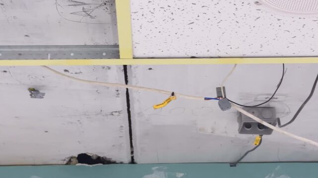 An electrical box and wires are fixed to the ceiling during renovation