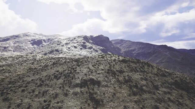 Cloudlit mountain slope with textured scrub, india atmospheric scene blending soft light and muted colors, expansive ridgeline framing distant peaks,