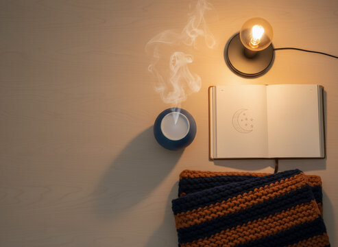 Mesa de noche con difusor de aromas, libro y luz c&aacute;lida antes de dormir
