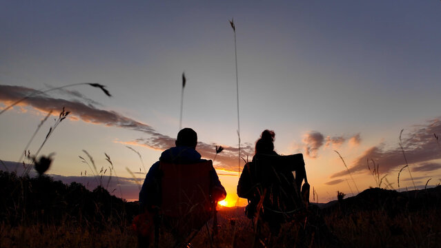 Man and woman looking at the sunset over the distant mountains.